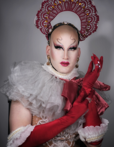 Lua wearing a grey tulle ruffled collar with bright red bow, red opera gloves, and a red lace headpiece.