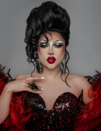 Zsa Zsa wearing a black sweetheart corset and red feather boa gazes into the camera.