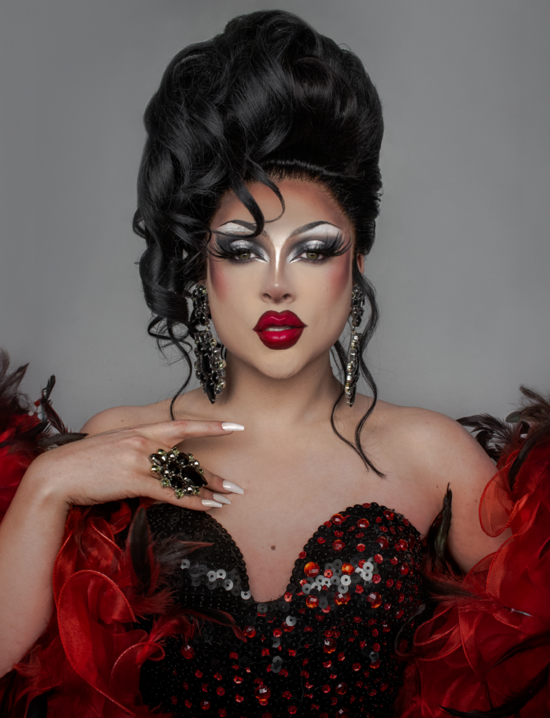 Zsa Zsa wearing a black sweetheart corset and red feather boa gazes into the camera.