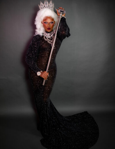 Aimee Yonce Shennel in a black rhinestone fitted gown, wearing a crown and holding a scepter.