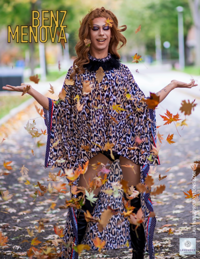 Benz Menova smiling in a leopard print poncho surrounded by floating autumn leaves.