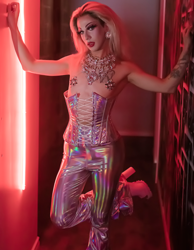 Benz Menova posting flirtatiously in a pink holographic outfit in a hallway.