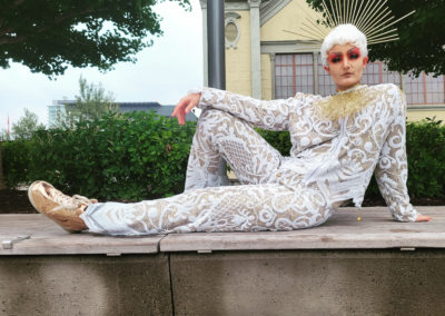 Cyril Cinder in a white lacy suit lounging on a bench.