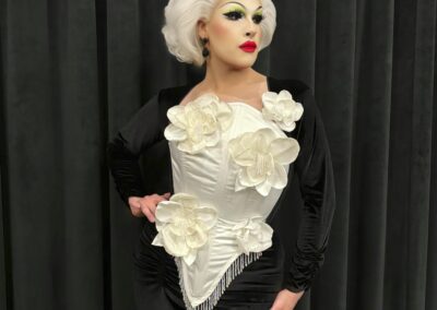 Edie Violet wearing a white flower corset over a black velvet dress.