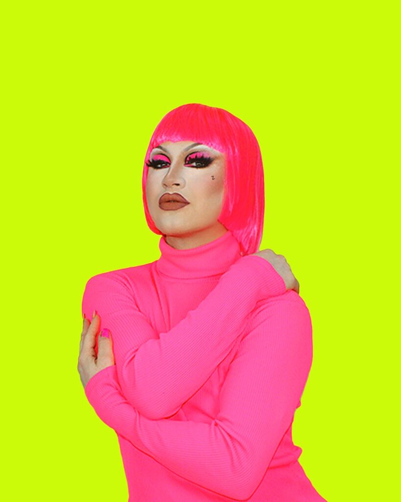 Zara Matrix with arms crossed, wearing a hot pink turtleneck and hot pink wig against a neon green background.