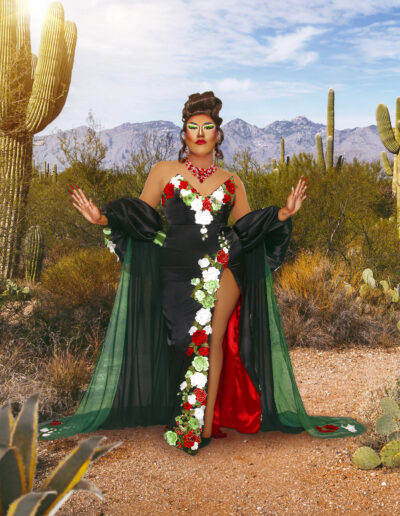 Dulce wearing a dark green slit dress with red and white flowers and a matching cape draped behind her.