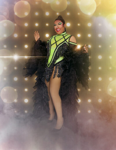 Dulce posing happily in a neon green and black flapper-style dress with a black frilly cape.