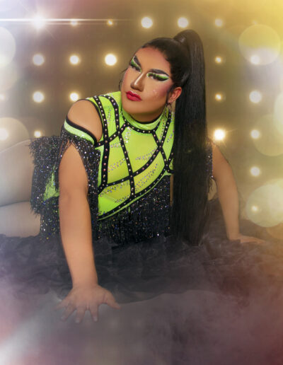 Dulce posing seductively on the floor wearing a neon green and black flapper-style dress.