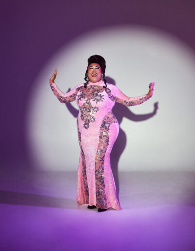 Dulce posing dramatically as she sings in the spotlight, wearing a pink and silver evening gown.