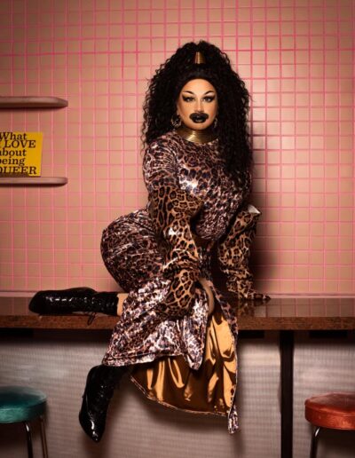 Halal Bae posing on a diner counter in a leopard print dress.