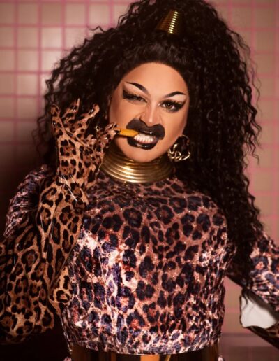 Bust view of Halal Bae in a leopard print dress, fiercely biting a French fry.