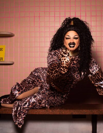 Halal Bae posing on a diner counter in a leopard print dress, growling with a clawed hand aimed at the camera.