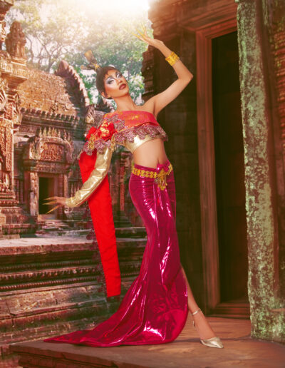 Phoenix Black wearing a red and gold two-piece outfit, posing dramatically with her left arm in the air and right arm trailing behind her.