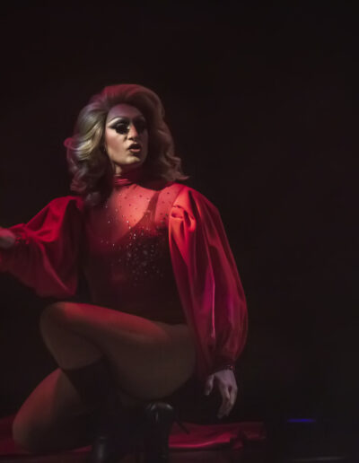 Aliya Holmes performing in a red rhinestone outfit with long flowy sleeves cinched at the wrist.