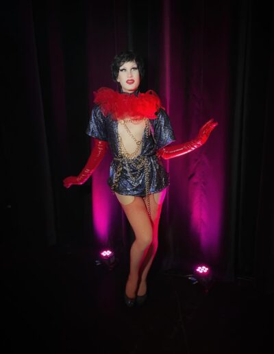 Lua in a black iridescent plunge neck dress with red feather boa and red opera gloves.