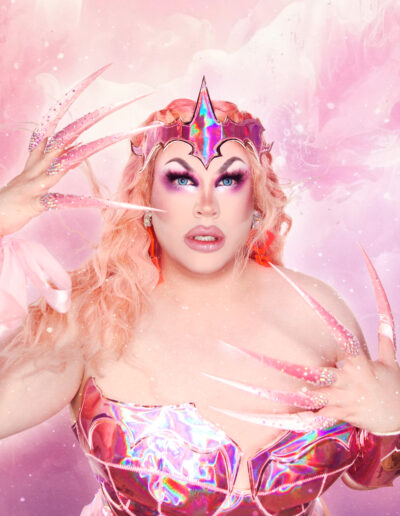 Bust-up view of Beth wearing a crystal themed pink iridescent bodysuit, holding her hands up to show off her long glittery claws.