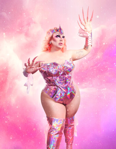 Beth wearing an iridescent pink bodysuit with matching thigh high boots, clawing at the air with exaggerated nails.