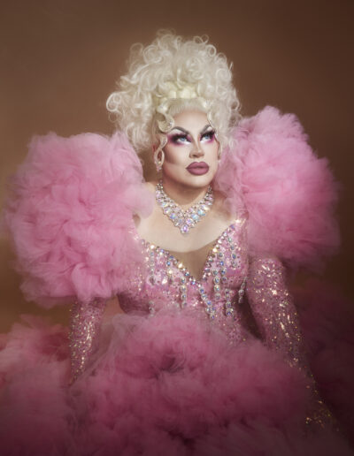 Beth wearing a pink dress with iridescent rhinestones on the bodice and sleeves with ruffled shoulders and skirt.