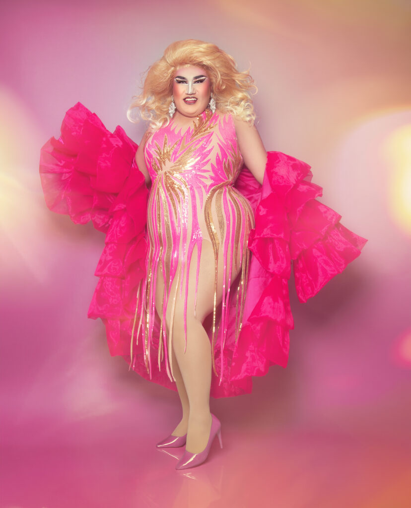 Dulce-PinkSmile Dulce wearing a pink fringed bodysuit with ruffled bright pink robe.